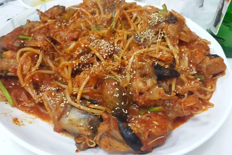 A large dish of agujjim, spicy braised monkfish with bean sprouts in a thick red chili sauce