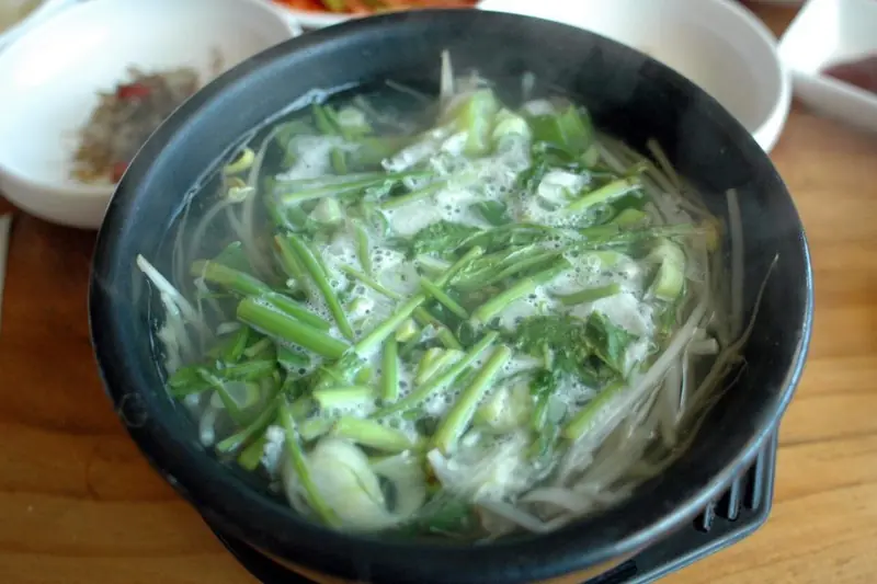 Bokguk clear pufferfish soup with bean sprouts and scallions in a pot