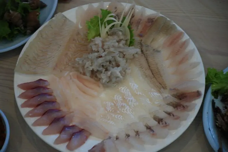 A platter of saengseon-hoe, thinly sliced Korean raw fish fanned out on a plate with shredded garnish