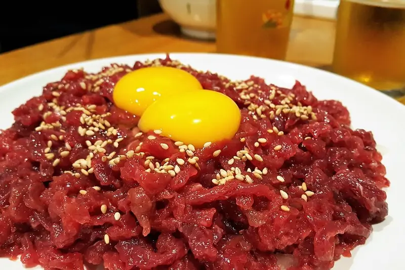 A mound of yukhoe, Korean seasoned raw beef tartare topped with a bright egg yolk and sesame seeds